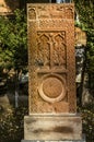 Red khachkar with animal reliefs, arches with crosses and the figure of a Saint on a horse on the alley of stone crosses in Gyumri