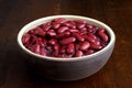 Red kidney beans in a dish in perspective. Isolated on dark wood. Royalty Free Stock Photo