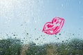 Red kiss lips painted with lipstick on the window with water drops. Background blue sunny sky, drops shine in the sun. Royalty Free Stock Photo