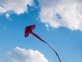 Red kite flying against blue sky with white clouds background. Royalty Free Stock Photo