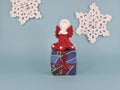 A red knitted angel stands on a New Year\'s gift. The gift is tied with a red ribbon.