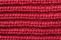 Red knitted fabric as an abstract texture. Knitting, elastic band pattern, English elastic band. Close-up.