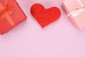 Red knitted heart between two gift boxes on a pink background Royalty Free Stock Photo