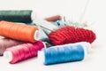 Red knitted needle pad for sewing and colored thread coils on white background with copy space for text Royalty Free Stock Photo