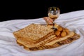 Red kosher wine with a white plate of matzah or matza and a Passover Haggadah on a vintage wood background