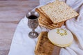 Red kosher wine with a white plate of matzah or matza and a Passover Haggadah on a vintage wood background presented as a Passover