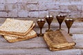 Red kosher wine with a white plate of matzah or matza and a Passover Haggadah on a vintage wood background presented as a Passover