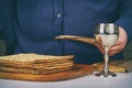 Red kosher wine with a white plate of matzah or matza and a Passover Haggadah on a vintage wood background presented as a Passover