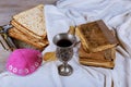 Red kosher wine with a white plate of matzah or matza and a Passover Haggadah on a vintage wood background