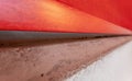 Red lacquered wood and raw cement surface close up background.