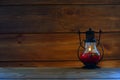 Red Lamp with a candle on the background of a wall lined with brown wood.