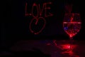 Red Laser light painting of Love sign for valentines day in a dark background with sparkling  wine glass for the celebration Royalty Free Stock Photo