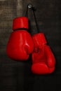 Red leather boxing gloves hanging on black wall