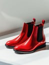 Red leather chelsea boots under sunlight.