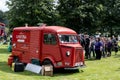 Red legendary French Citroen Type H van in a green park providing snacks to customers in a long queue