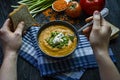 Red lentil cream soup decorated with fresh vegetables and herbs. A man eats soup. Veggie concept. Proper nutrition Royalty Free Stock Photo