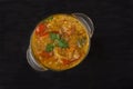 Red lentil soup in a glass bowl with spices, herbs, onion and garlic on a black background. Copy spaes Royalty Free Stock Photo