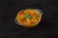 Red lentil soup in a glass bowl with spices, herbs, onion and garlic on a black background. Copy spaes Royalty Free Stock Photo