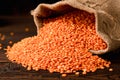 Red lentils in a jute bag on a wooden table