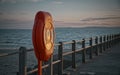 Red life buoy with metal railings and a blue sea background in a sunset Royalty Free Stock Photo