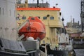 The red lifeboat of the icebreaker Mudyug against the background of the ship`s superstructure of the icebreaker Ivan Kruzenshtern