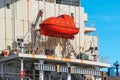 Vibrant Red Lifeboat Securely Fastened to Modern Ship with White Background