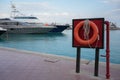 Red lifebuoy at a blue ocean bay with a luxury yacht in the background Royalty Free Stock Photo