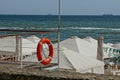 Red lifebuoy on the fence of white arbours of cloth on the beach near the sea waves Royalty Free Stock Photo