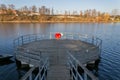 Red lifebuoy hanging on wooden pier, Jordan pond, Tabor, oldest dam in the Czech Republic, sunny autumn day, life insurance Royalty Free Stock Photo