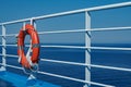 a red lifebuoy hangs on board a ferry cruise ship against the backdrop of a blue sea and a cloudless sky Royalty Free Stock Photo