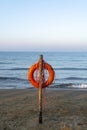 Red lifebuoy with rope on sandy beach, life save in sea water concept