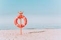 red lifebuoy on a sandy beach in pastel colors. Red lifebuoy on the sandy shore of the beach on a sunny day against the Royalty Free Stock Photo