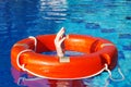 Red lifebuoy on the surface of the water in the pool and the hands of a man grabbing it Royalty Free Stock Photo
