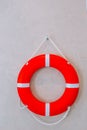 Red lifebuoy with white strip hanging on white wall , had space on left side for creative. safety on the water Royalty Free Stock Photo