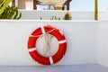 Red lifebuoy with white strip hanging on white wall , had space on left side for creative Royalty Free Stock Photo