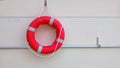 Red lifebuoy with white strip hanging on white wall Royalty Free Stock Photo