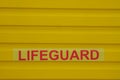 Red lifeguard sign on a yellow color metal wall. Safety and human care concept