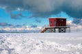 Red lifeguard tower or rescue tower on the snow covered beach Royalty Free Stock Photo