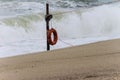 Red lifesaver on beach with breaking huge waves