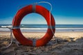 Red lifesaver ring standing upright on a beach