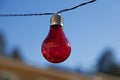A red light bulb hanging outdoors Royalty Free Stock Photo