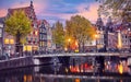Red-light district in Amsterdam city picturesque landscape panorama evening town with pink sunset sky. Bridge over canal river