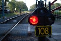 Red light switched on the side of a empty train track with a number on a plaque underneath it