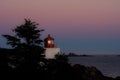 Red lighthouse behind trees at sunset in Vancouver Island Royalty Free Stock Photo