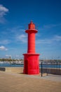 The red Lighthouse of Cambrils Port, background the coastline of the town