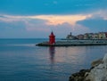 Red lighthouse on coastline of Adriatic sea with colorful houses at sunset, Piran, Slovenia Royalty Free Stock Photo