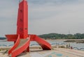 Red lighthouse with curved staircase on concrete dock of seaport