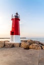 Red lighthouse at the end of the harbour breakwater during the summer sunset Royalty Free Stock Photo