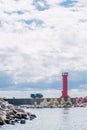 Red lighthouse on end of pier with truck parked to the left side