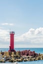 Red lighthouse on end of pier with two men sitting at base in shadow